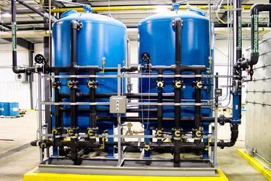 Industrial setting with large blue water tanks and black piping system.