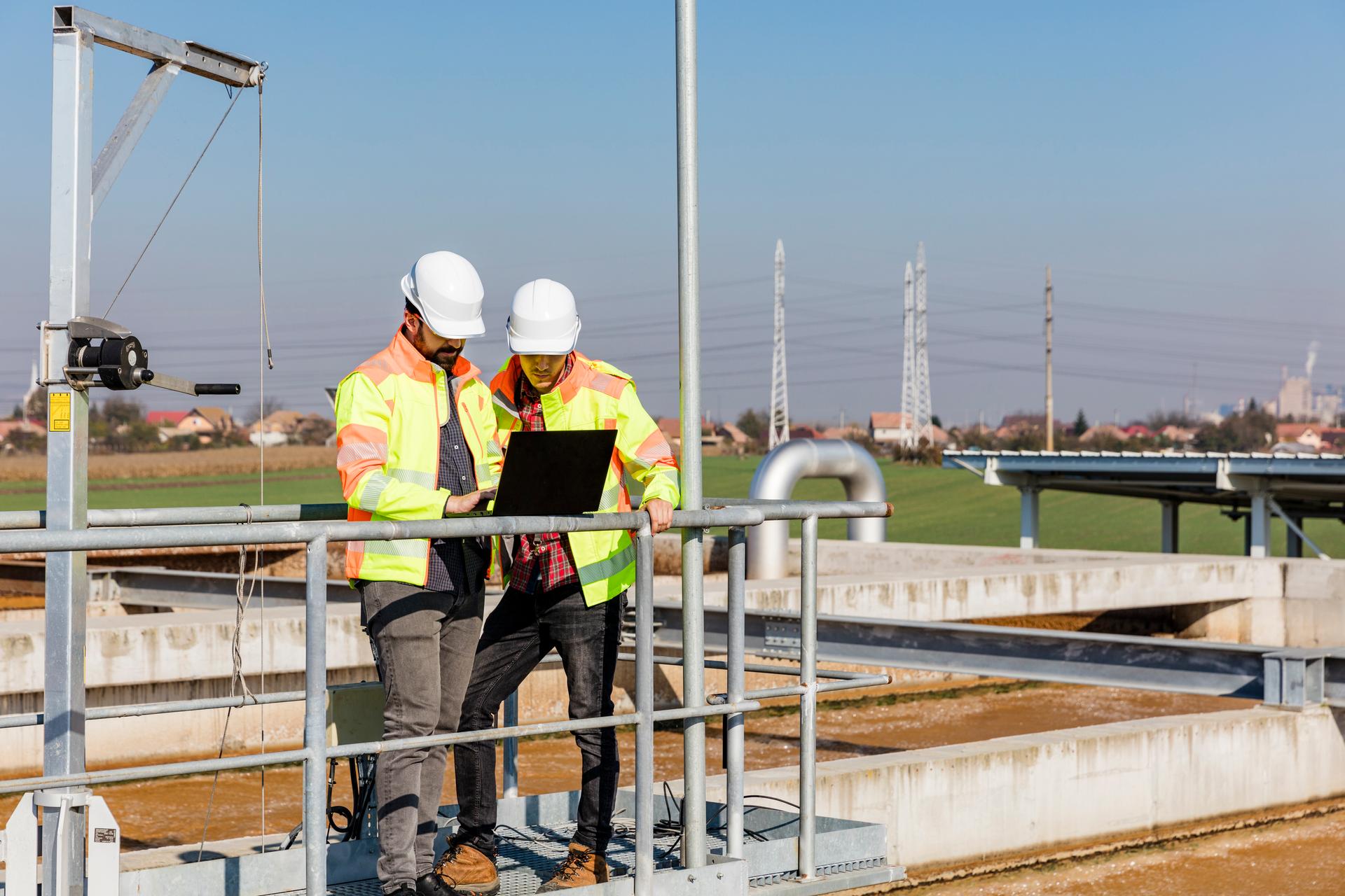 Engenheiros que trabalham na estação de tratamento de água com laptop